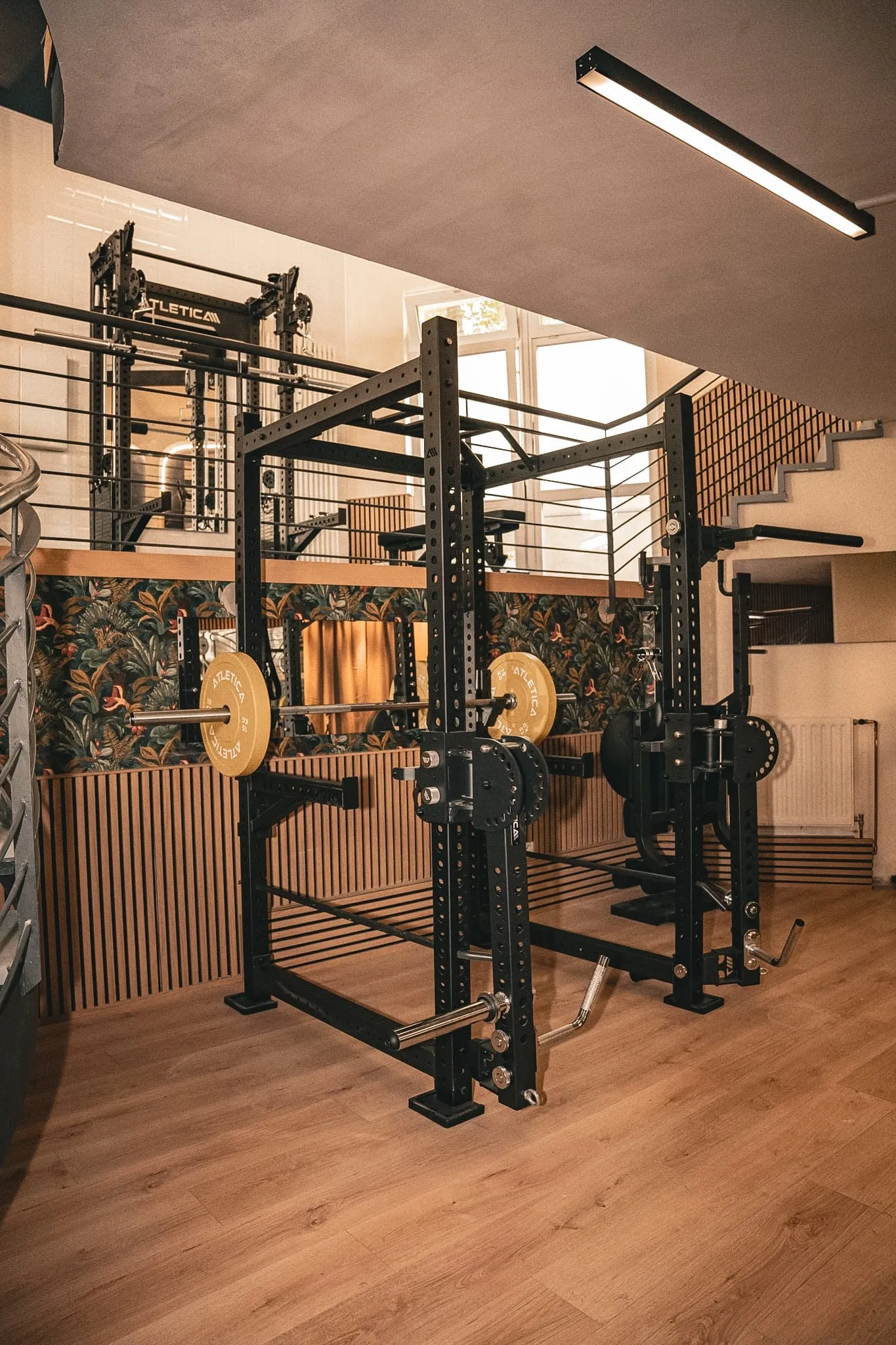 Kraftstation mit Hantelablage vor einer Wand aus Holzlamellen im Trainingsstudio.